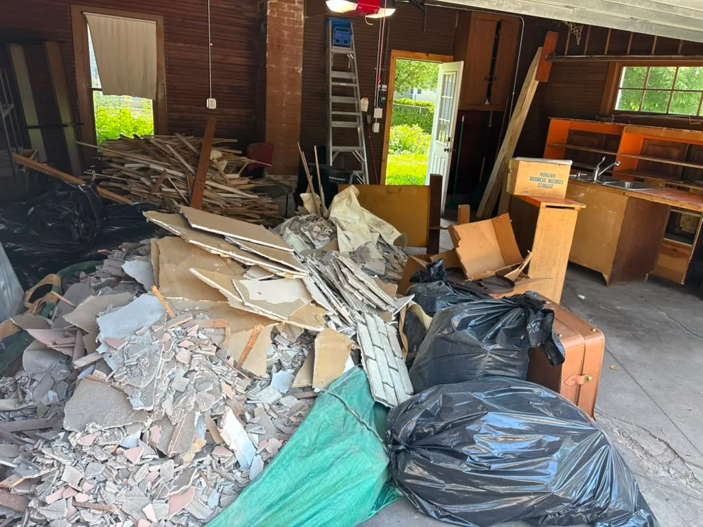 Drywall, wood and bagged renovation debris ready for removal inside a property