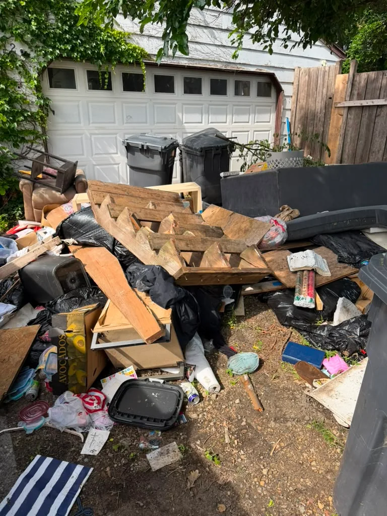 Furniture, wood and household items gathered outside a garage for a property cleanout